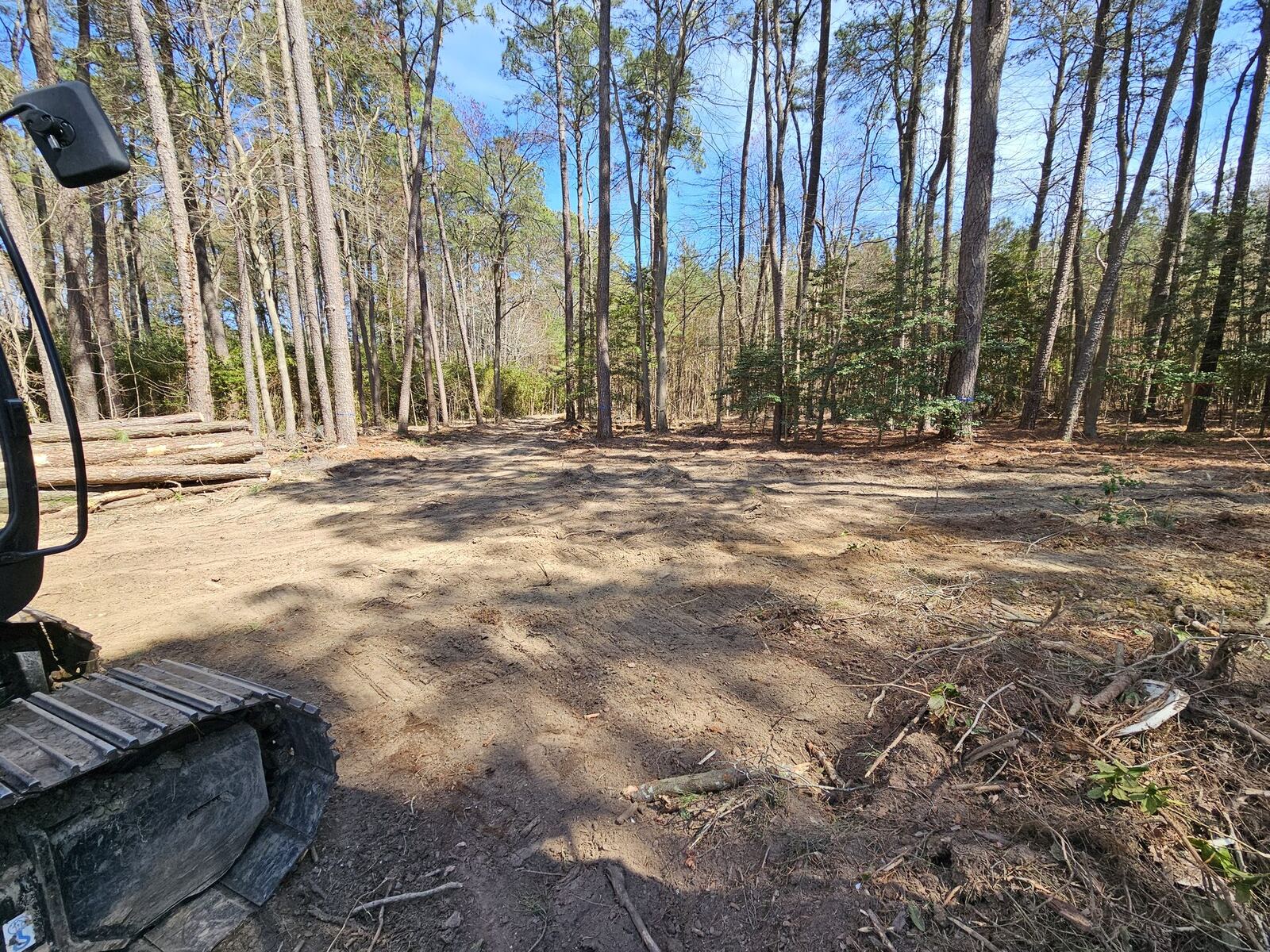 Land clearing project with burn pile and excavator on a Virginia property
